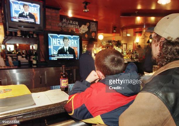 Jody Easton and his nine-year-old son Cody watch televisions inside Wayne Gretzky's restaurant called Wayne Gretzky's 16 April 1999 in Toronto as...