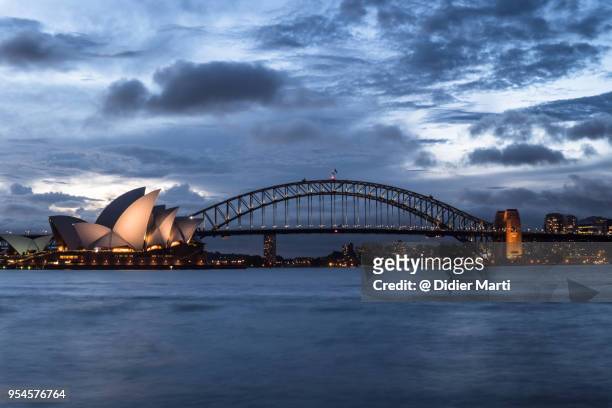 stunning twilight over the famous sydney opera house and the harbour bridge - opera house stockfoto's en -beelden