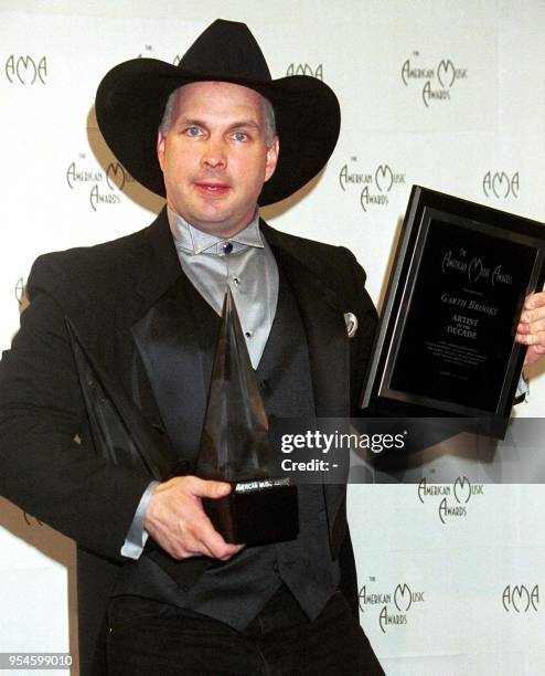 Country singer Garth Brooks poses with his three awards for favorite country male artist, favorite country album, and artist of the decade at the...
