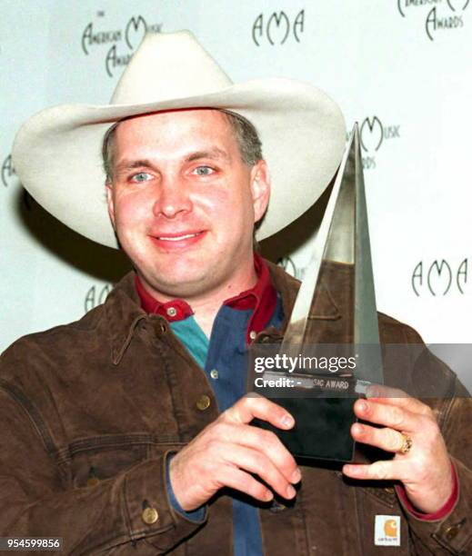 Country singer Garth Brooks holds the award he received at the 22nd Annual American Music Awards 30 January 1995 in Los Angeles. Brooks won favorite...