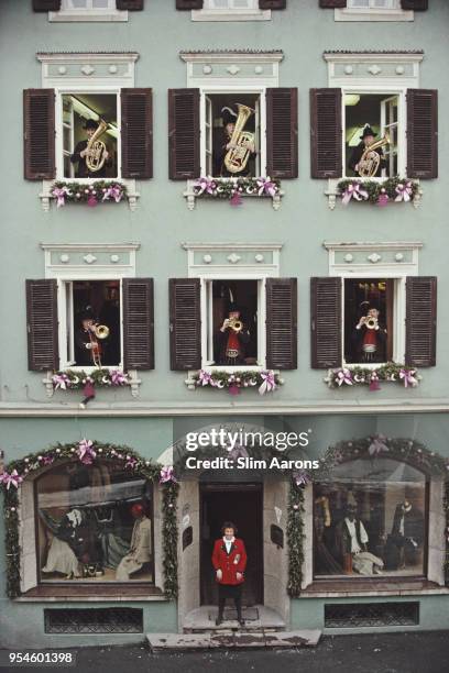 Edeltraud 'Traudi' Eder standing near the doorway of her 'Trachten Sport Couture' boutique, while musicians appear from the shop's windows and...
