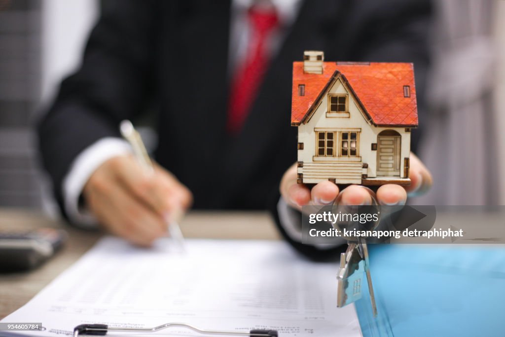 House key in home insurance broker agent's hand protection or in salesman person giving to buyer customer