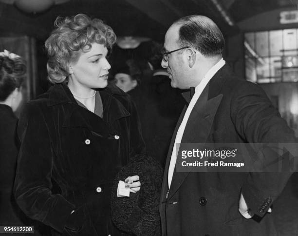 French actress Simone Signoret talks to producer Michael Balcon at the premiere of the film 'The Life and Adventures of Nicholas Nickleby' at the...
