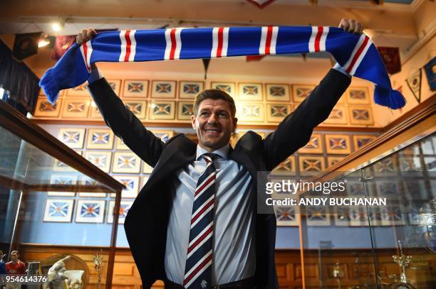 Former England and Liverpool captain Steven Gerrard smiles as he holds up a Rangers scarf in the trophy room as he is unveiled as Rangers' new...