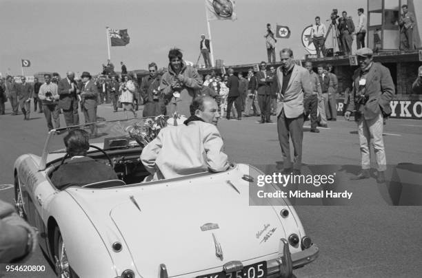 British Formula One driver Stirling Moss sitting in the back of a car after the Dutch Grand Prix, in which he placed fourth but first in the Drivers'...