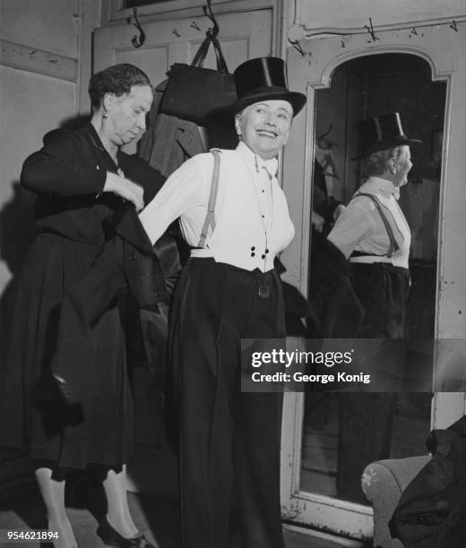 Music hall singer and male impersonator Ella Shields is helped into her tail coat before going on stage, October 1948. She will appear in the Royal...