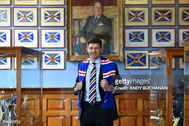 Former England and Liverpool captain Steven Gerrard smiles as he poses for a photograph with a Rangers scarf, in front of the portrait of former...