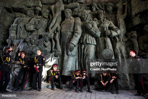 Young Ukrainian cadets rest in the shadow of a sculptural composition after parading at the WWII open-air museum in Kiev on May 4, 2018. Some 700...