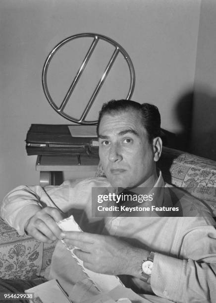 American bandleader and musician Artie Shaw opens his mail in his London hotel room, 1951.