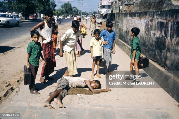 Cadavre d'un mendiant sur le sol entouré d'enfants à Dacca en novembre 1974, Bangladesh.