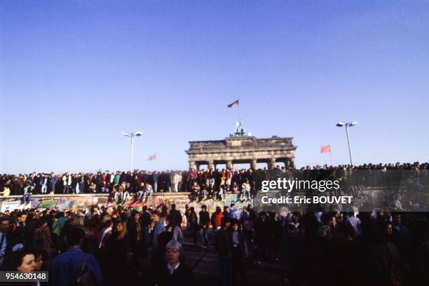 Berlinois assis sur le mur devant la Porte de Brandebourg lors de la chute du Mur de Berlin le 10 novembre 1989, Allemagne.