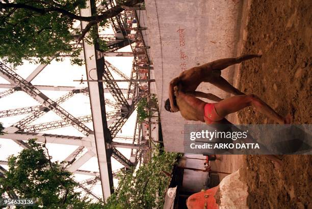 Wrestlers practice on the banks of the River Ganges beneath Howrah Bridge 05 July in the eastern Indian city of Calcutta. People of different ages...