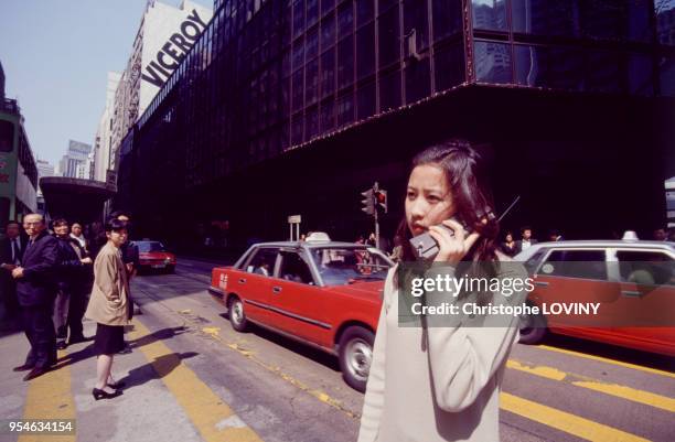 Jeune femme utilisant un téléphone portable dans une rue de Hong-Kong en 1991, Chine.