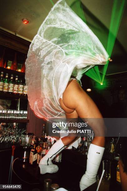 Une gogo danseuse des Bains Douches fait le spectacle juchée sur un comptoir de bar en janvier 2000 à Paris, France.