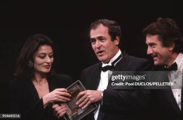 Le metteur en scène Bernardo Bertolucci entouré d'Anouk Aimée et Robert De Niro le 7 mai 1987 à Cannes, France.