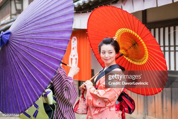 twee vrouwen onder de paraplu's praten en smilling, kyoto, japan - lypsekyo16 stockfoto's en -beelden