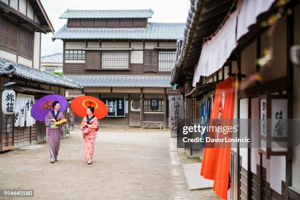 als in moderne tijden, twee vrouwen lopend en pratend op een oude straat in japan - lypsekyo16 stockfoto's en -beelden