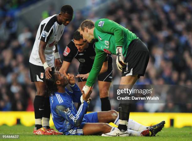 Didier Drogba of Chelsea is assisted by John Pantsil and Mark Schwarzer of Fulham as referee Andre Marriner looks on during the Barclays Premier...