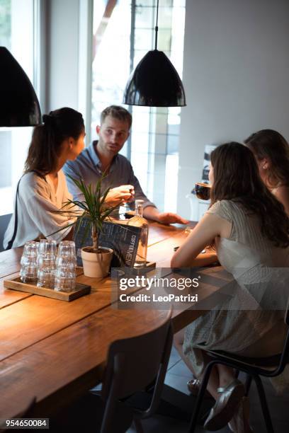 friends celebrating at lunch with food and drink in a modern cafe in the city - cafe culture stock pictures, royalty-free photos & images
