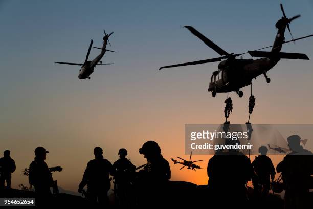 silhouettes of soldiers on military mission at dusk - conflict stock pictures, royalty-free photos & images