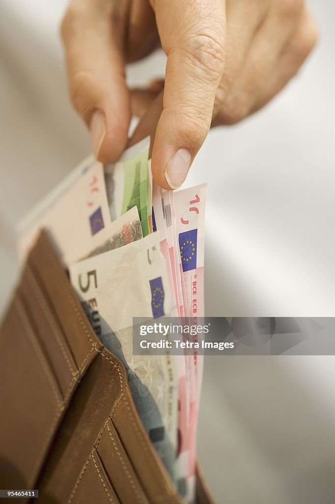 Fingers pulling out money from a wallet