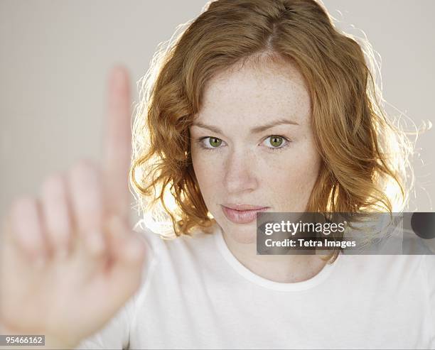 a woman gesturing with one finger up - doigt levé photos et images de collection