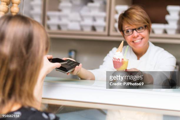 vrouwen gebruik contactloze betalingen in een ijs winkel - focus op pad - pjphoto69 stockfoto's en -beelden