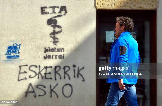 Man walks past a graffiti showing the Basque separatist group ETA logo and the text in Basque "Thanks a lot" in the Spanish Basque village of...