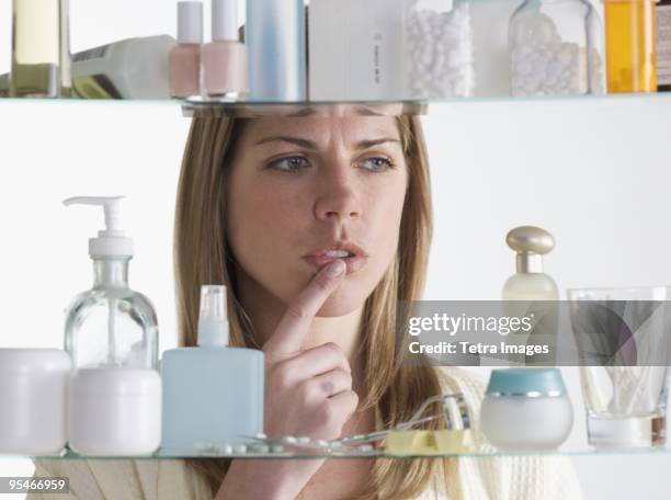 woman looking in medicine cabinet - bathroom cabinet stock pictures, royalty-free photos & images