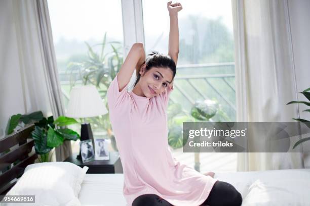 beautiful woman stretching on bed - waking up stock pictures, royalty-free photos & images
