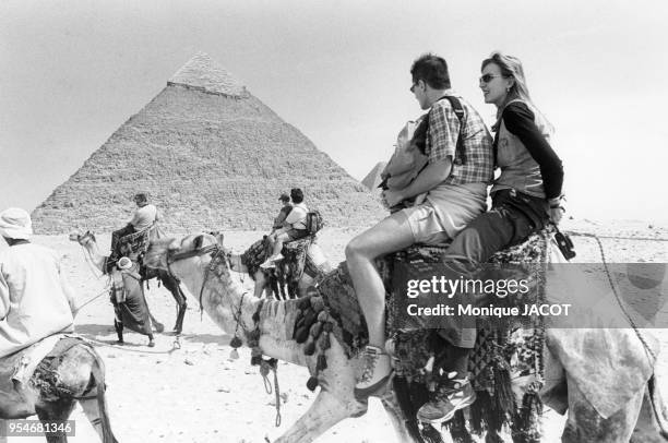 Touristes sur des dromadaires devant la pyramide de Khéops à Gizeh, en 2000, Egypte.