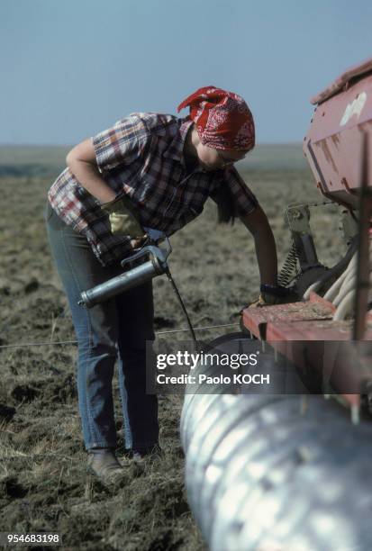 Agricultrice mettant de l'huile dans son tracteur au Canada, en Alberta, en 1975.