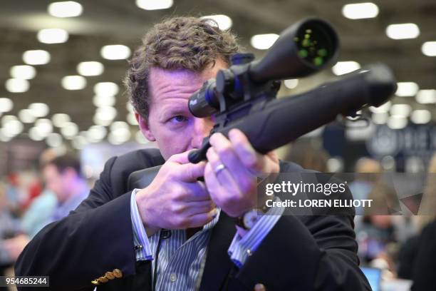 Jeffrey Kimbell looks through a rifle scope in an exhibit hall at the NRA's annual convention on May 4, 2018 in Dallas, Texas.