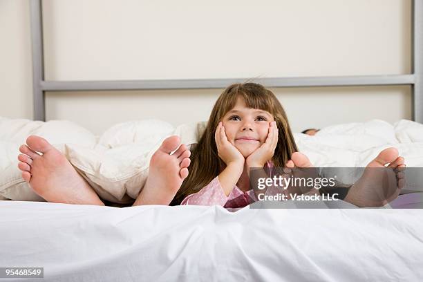 family in bed - woman lying on stomach with feet up foto e immagini stock