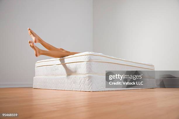 legs hanging off bed - materasso foto e immagini stock