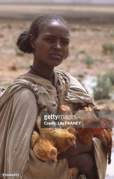 Portrait d'une jeune femme transportant des poules en Ethiopie, en 1985.