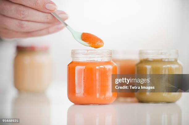 hand spooning baby food - tetra images stock-fotos und bilder