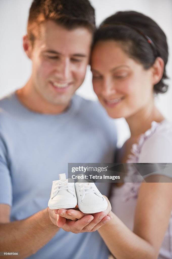 Couple holding baby shoes