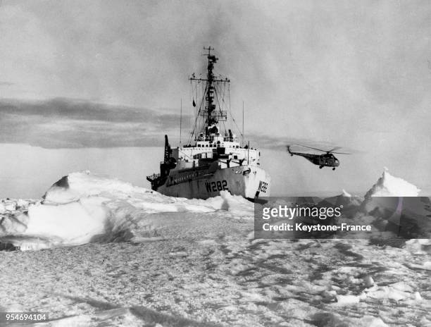 Brise-glace en action guidé par un hélicoptère en Antarctique.