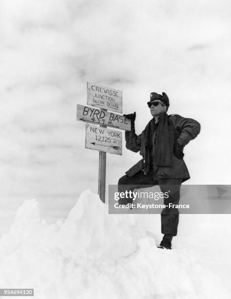 Un membre des Forces navales américaines est photographié auprès d'un panneau de signalisation posé au milieu de la neige, en Antarctique.