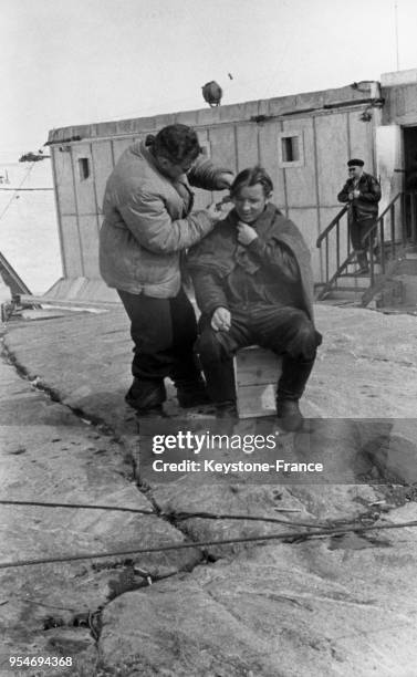 Sur la base soviétique Mirny, un coiffeur coupe les cheveux d'un homme à l'extérieur, en Antarctique en avril 1959.