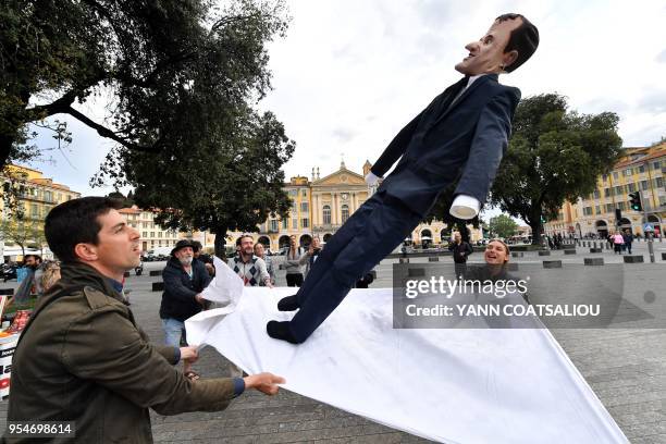 People throw an effigy of French President Emanuel Macron into a sheet, a local carnival tradition in Nice, southern France on May 4 on the eve of a...