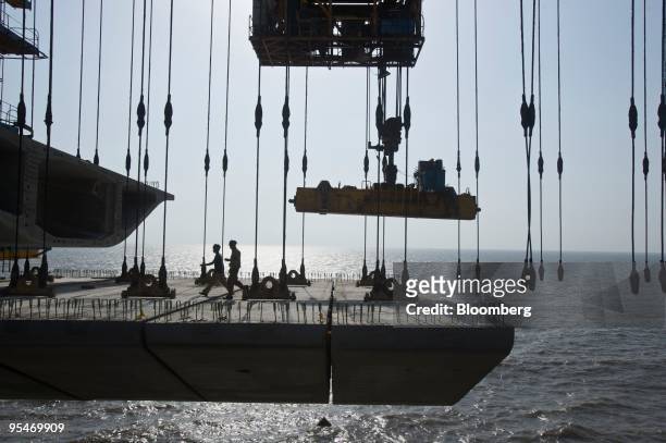 Laborers walk on a section of the Bandra-Worli sea link over the water in Mumbai, India, on Tuesday, May 5, 2009. The Bandra-Worli sea link will join...