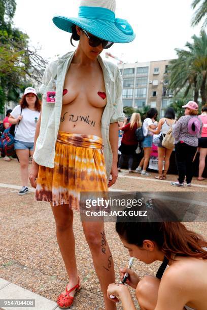 Graphic content / A participant of the annual "SlutWalk" draws slogans with a marker on another's leg during the march in the Israeli Mediterranean...