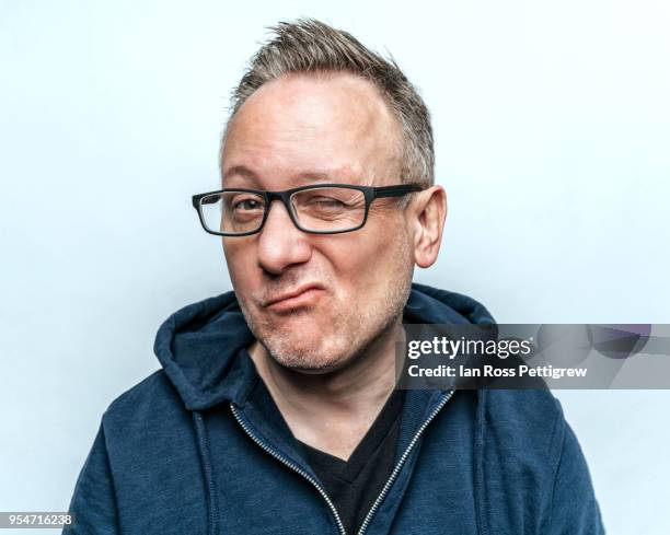 middle-aged man wearing a blue hoodie winking at camera - zwinkern stock-fotos und bilder
