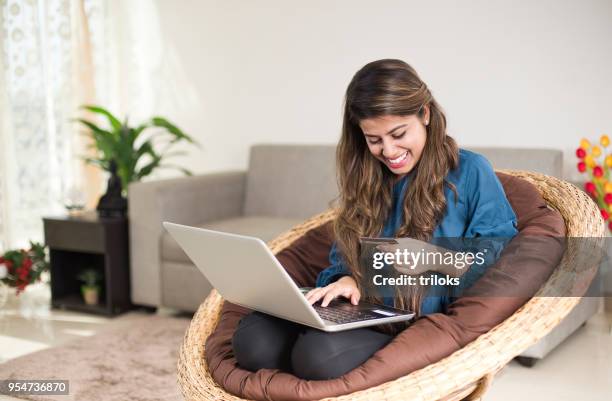 女性が家庭でオンライン ショッピングを行う - ビーズソファ ストックフォトと画像
