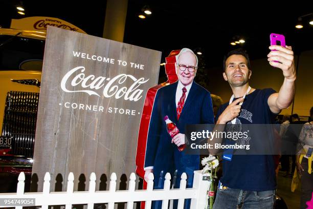 An attendee takes a selfie photograph with a cardboard cutout of Warren Buffett, chairman and chief executive officer of Berkshire Hathaway Inc., at...