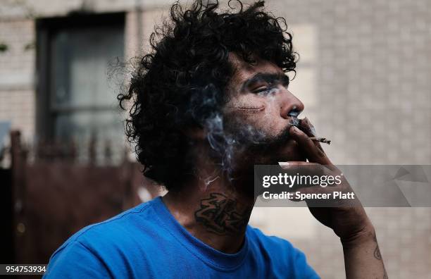 Eliezer, a 38 year old homeless heroin addict, smokes a K2 cigarette in the Bronx on May 4, 2018 in New York City. Eliezer often snorts his heroin...