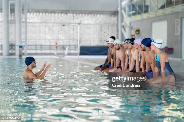 swimming coach giving instructions to his class before they get into the pool - swim coach stock pictures, royalty-free photos & images