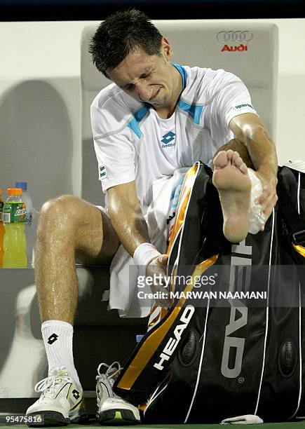 Ukranian Sergiy Stakhovsky puts ice on his ankle after hurting himself during his ATP tennis match against Britain's Andy Murray on the first day of...